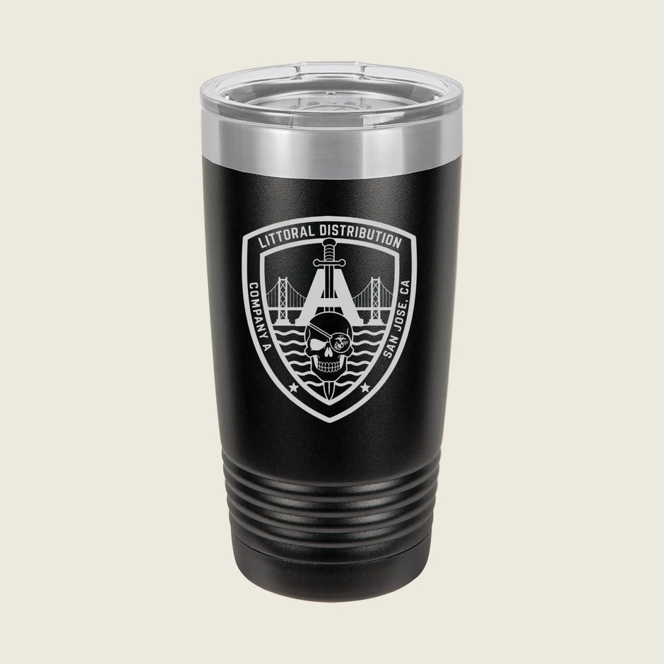 A black insulated travel tumbler with a clear lid, featuring a white and gray shield emblem on the front that reads 'Litoral Distribution' with a bridge and skull graphic, set against a light beige background.