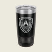 A black insulated travel tumbler with a clear lid, featuring a white and gray shield emblem on the front that reads 'Litoral Distribution' with a bridge and skull graphic, set against a light beige background.