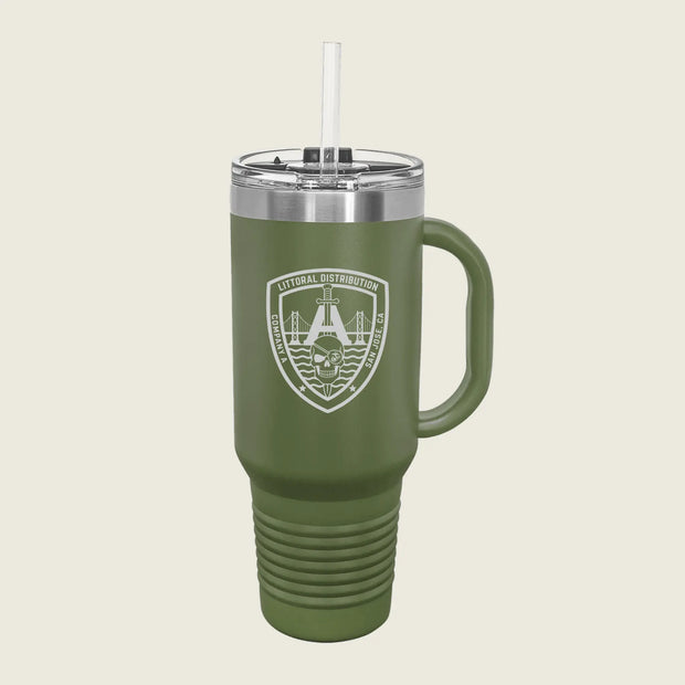 An olive green insulated travel tumbler with a handle, clear lid, and straw, featuring a white printed military-style crest on the front, shown on a light beige background.