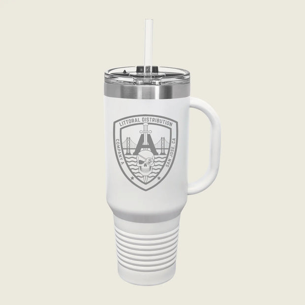 A white insulated travel tumbler with a handle, clear lid, and straw, featuring a gray shield logo that reads 'LITORAL DISTRIBUTION' with a bridge and skull graphic, on a light beige background.