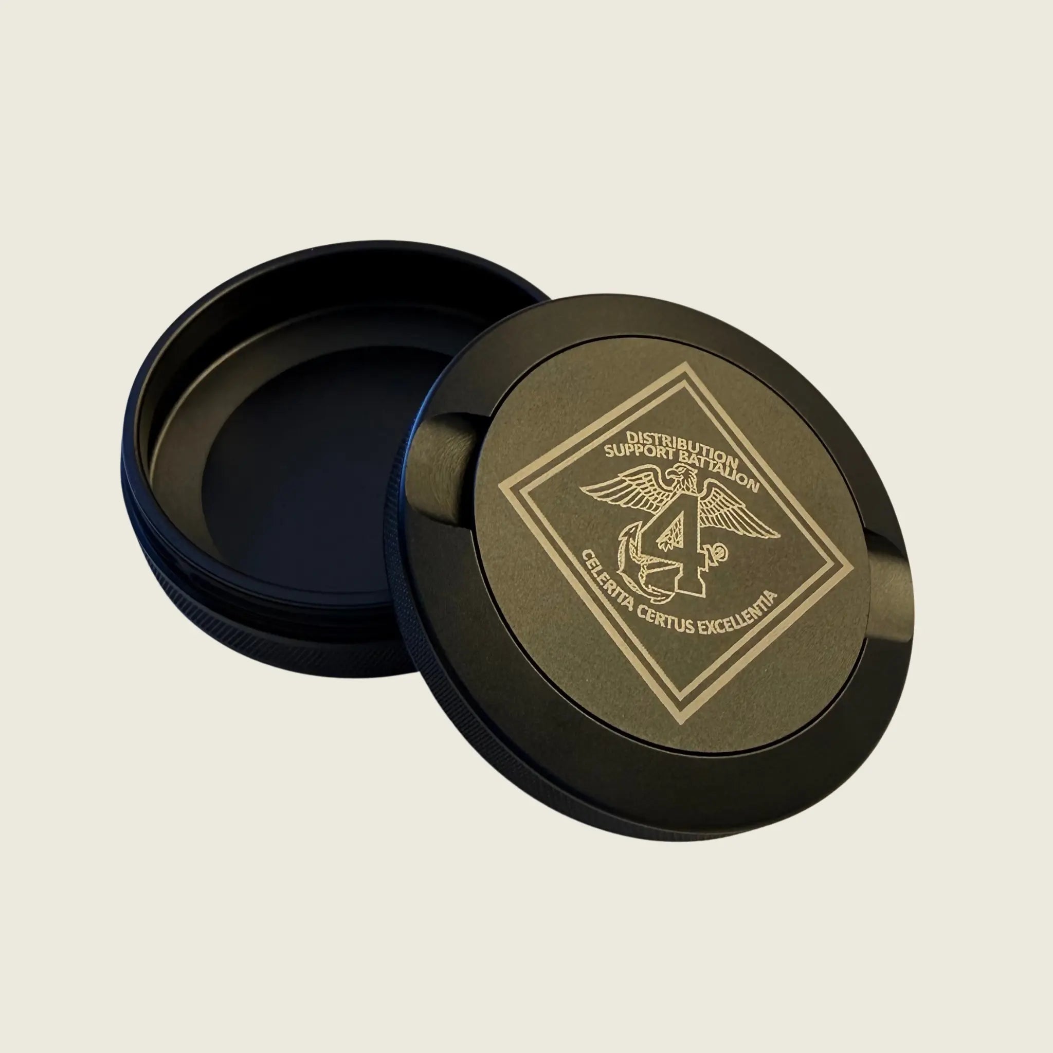 Round black container with gold lid featuring a logo on a beige background
