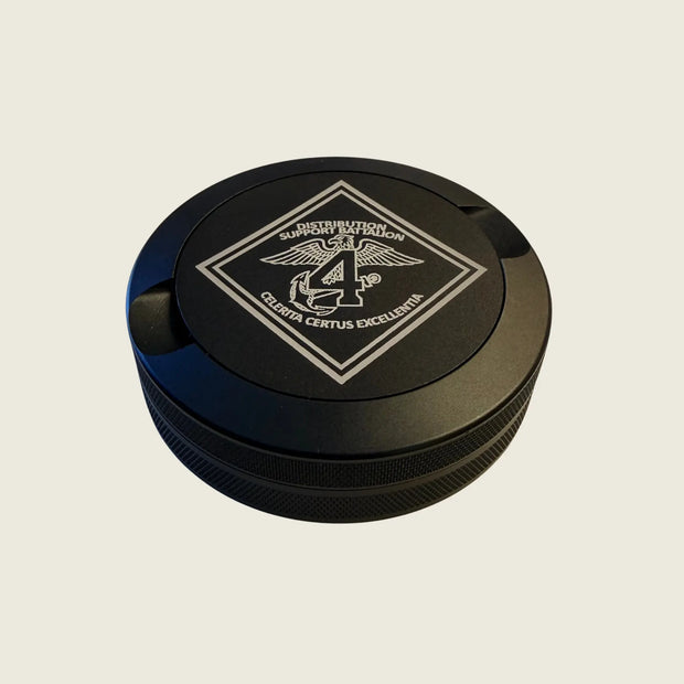 Black circular object with a logo on a beige background