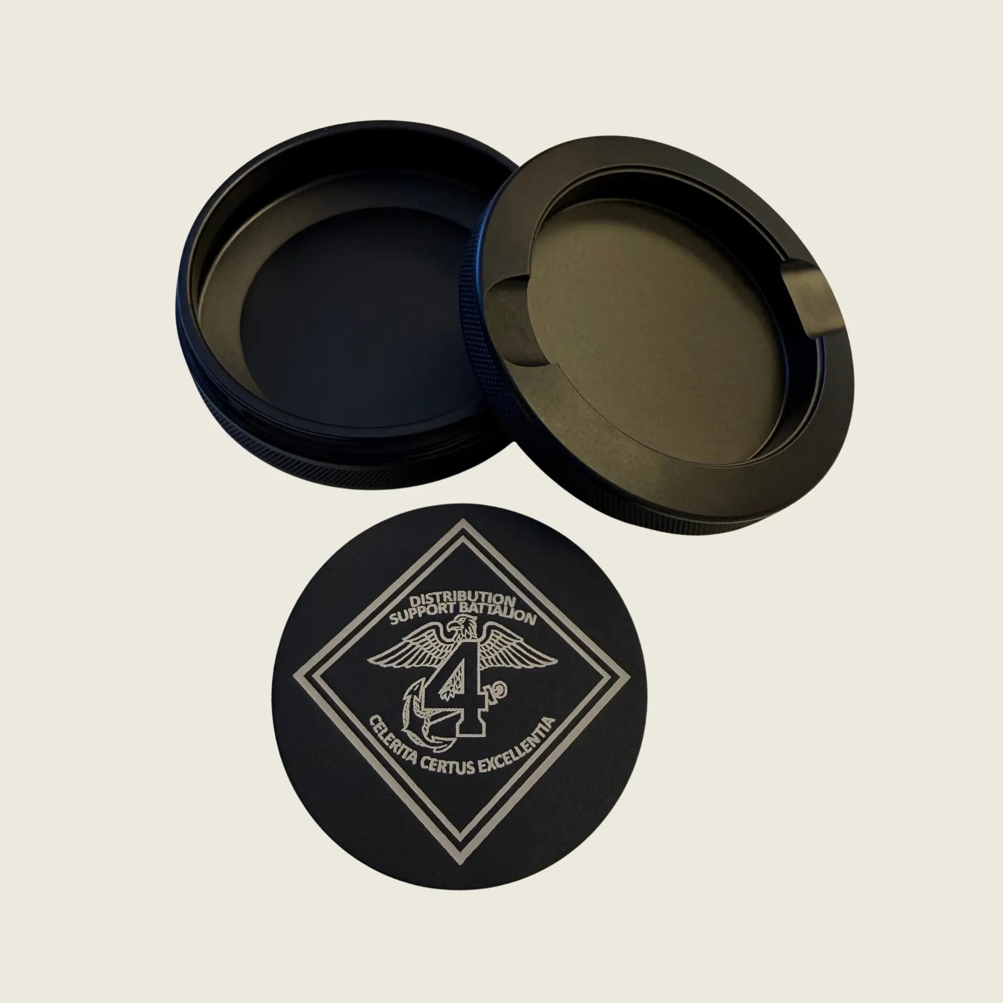 Black container with lid and base featuring a logo on a beige background