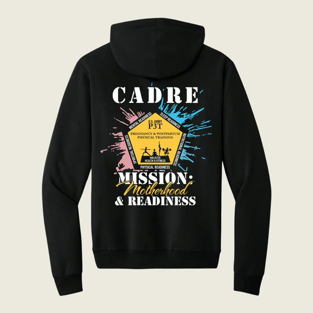 A black pullover hoodie shown from the back, featuring a colorful graphic print with the text 'CADRE' and 'MISSION: Motherhood & Readiness' around a central yellow badge design, on a light beige background.