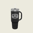 A black insulated travel tumbler with a handle, clear lid, and white straw, featuring a white graphic print that reads 'ASSASSINS' The tumbler is centered on a light beige background.