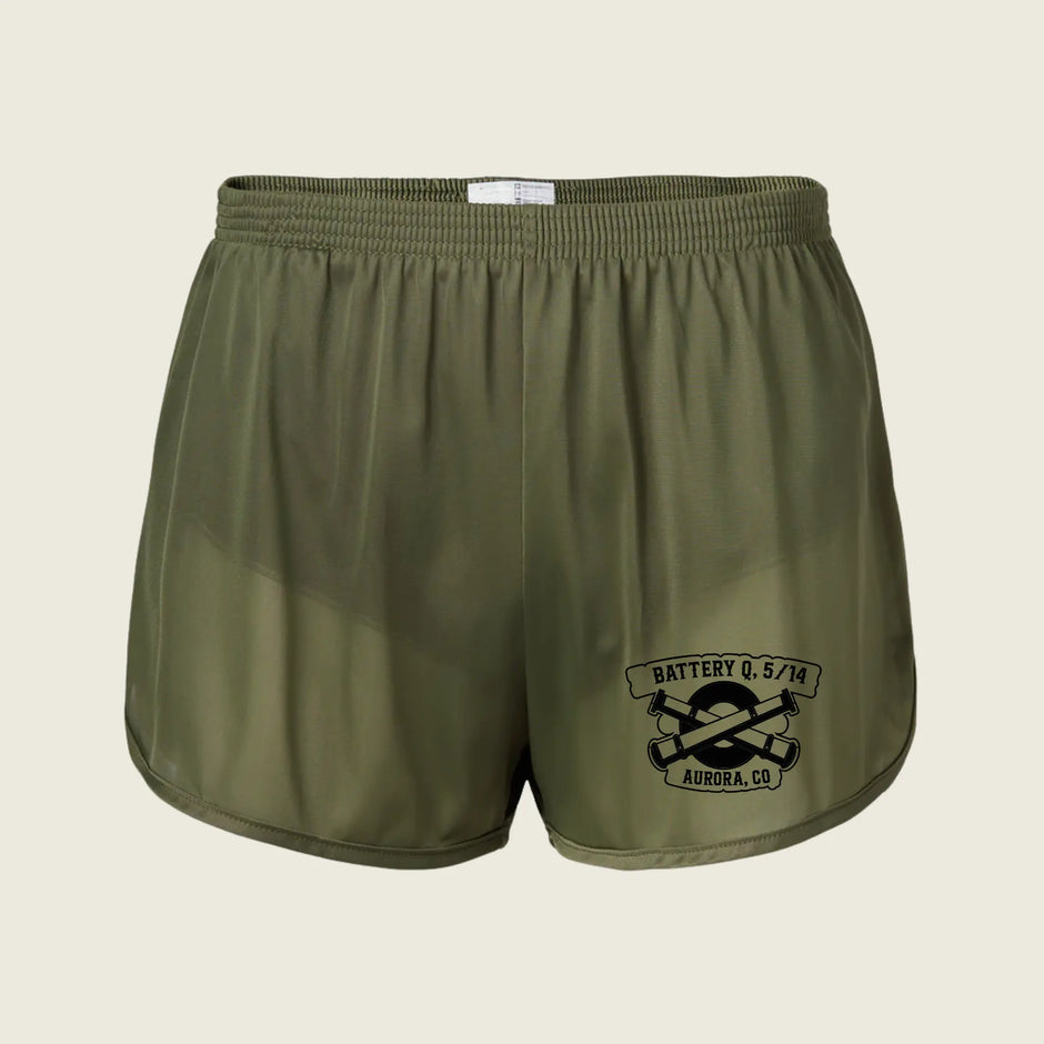 Olive green athletic shorts with a black graphic print on the lower left leg that reads 'BATTERY Q. 5/14 AURORA, CO' with crossed tools, shown on a light beige background.
