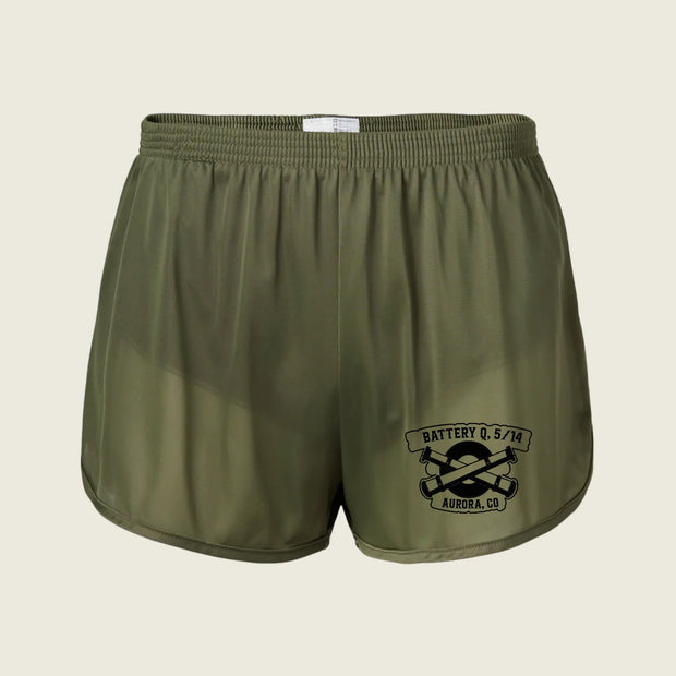 Olive green athletic shorts with a black graphic print on the lower left leg that reads 'BATTERY Q. 5/14 AURORA, CO' with crossed tools, shown on a light beige background.
