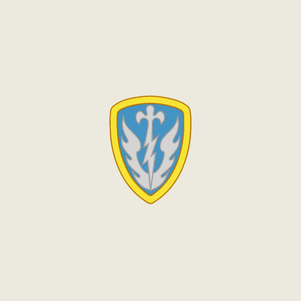 A shield-shaped emblem with a yellow border, light blue center, and a white stylized bird or flame motif, centered on a plain light beige background.