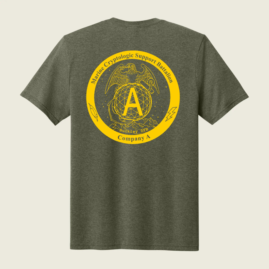 A heather olive green t-shirt shown from the back, featuring a large yellow circular graphic print with the USMC Eagle, Globe, and Anchor emblem and the text 'Marine Cryptologic Support Battalion Company A'.