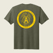 A heather olive green t-shirt shown from the back, featuring a large yellow circular graphic print with the USMC Eagle, Globe, and Anchor emblem and the text 'Marine Cryptologic Support Battalion Company A'.