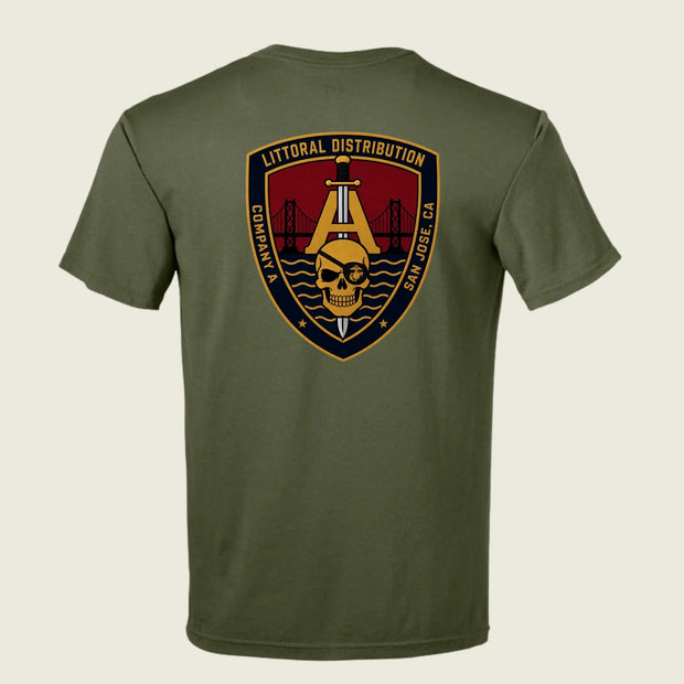 An olive green short-sleeve t-shirt shown from the back, featuring a large military-style shield patch graphic on the upper back with a skull, bridge, and text reading 'LITTORAL DISTRIBUTION' and 'COMPACT SAN JOSE CA'.