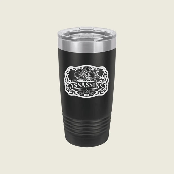 A black insulated travel tumbler with a clear lid and a white 'Assassins' graphic on the front, set against a solid light beige background.