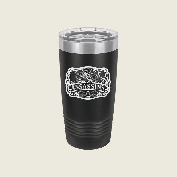 A black insulated travel tumbler with a clear lid and a white 'Assassins' graphic on the front, set against a solid light beige background.