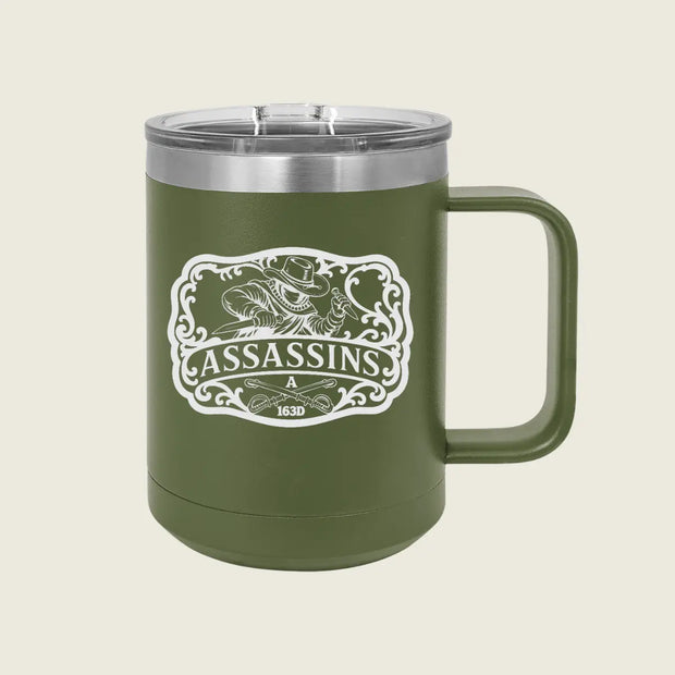 An olive green insulated travel mug with a stainless steel lid and a white 'Assassins' graphic on the front, set against a solid light beige background.