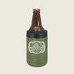 An olive green insulated bottle sleeve with a black top band holding a brown glass bottle, shown on a light beige background. The sleeve features a white graphic with the word 'ASSASSINS'