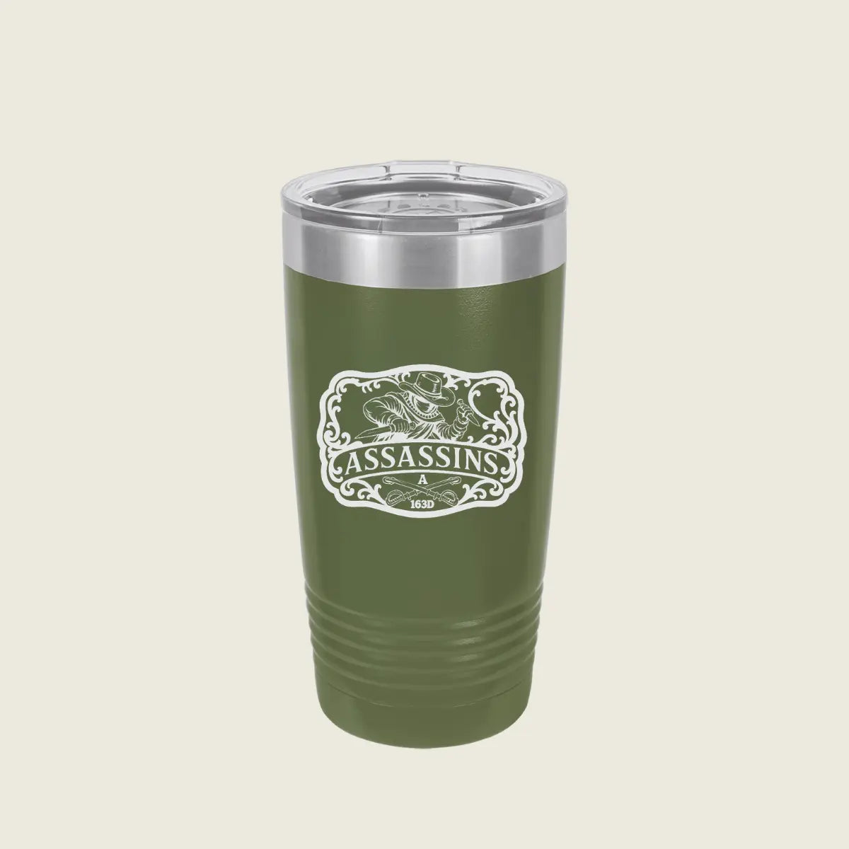 A green insulated travel tumbler with a clear lid and a white 'Assassins' graphic on the front, set against a solid light beige background.