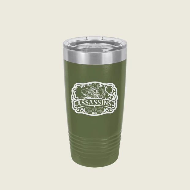 A green insulated travel tumbler with a clear lid and a white 'Assassins' graphic on the front, set against a solid light beige background.