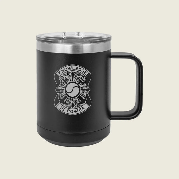 A matte black insulated travel mug with a clear lid and a black handle, featuring a white graphic design on the front that reads 'KNOWLEDGE IS POWER' around a circular emblem. The mug is photographed against a solid, light beige background.