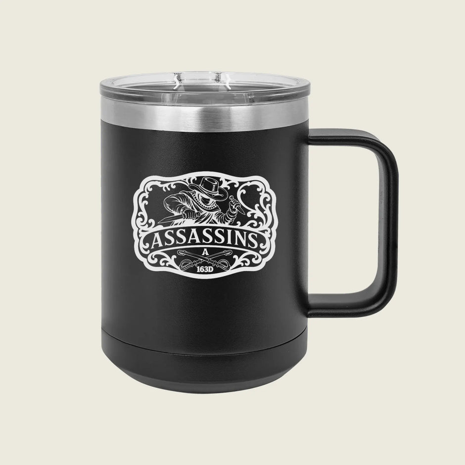 A black insulated travel mug with a clear lid and a black handle, featuring a white graphic design on the front with the word 'ASSASSINS' and a stylized illustration, set against a light beige background.