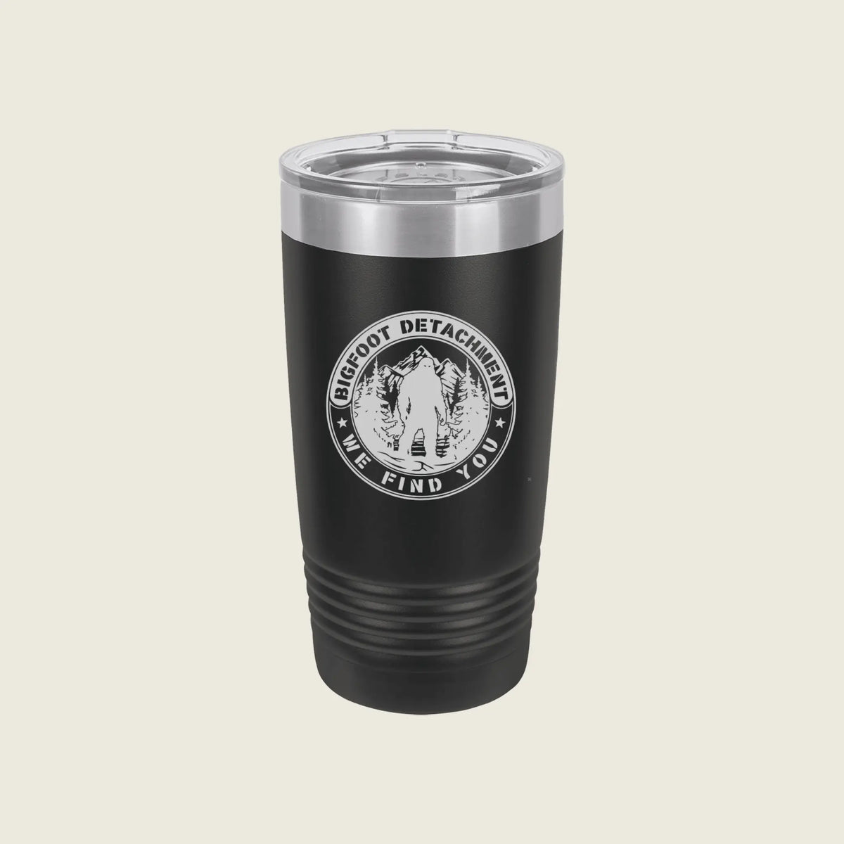 A black insulated travel tumbler with a clear lid, featuring a circular white graphic that reads 'BIG FOOT DETACHMENT WE FIND YOU' around an illustration of a person in a forest.