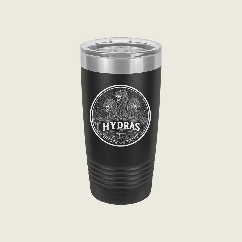 A black insulated travel tumbler with a clear lid, featuring a circular silver graphic of two horses and the word 'HYDRAS' on the front, set against a solid light beige background.