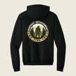 Black hoodie with Bigfoot Detachment graphic on the back against a beige background