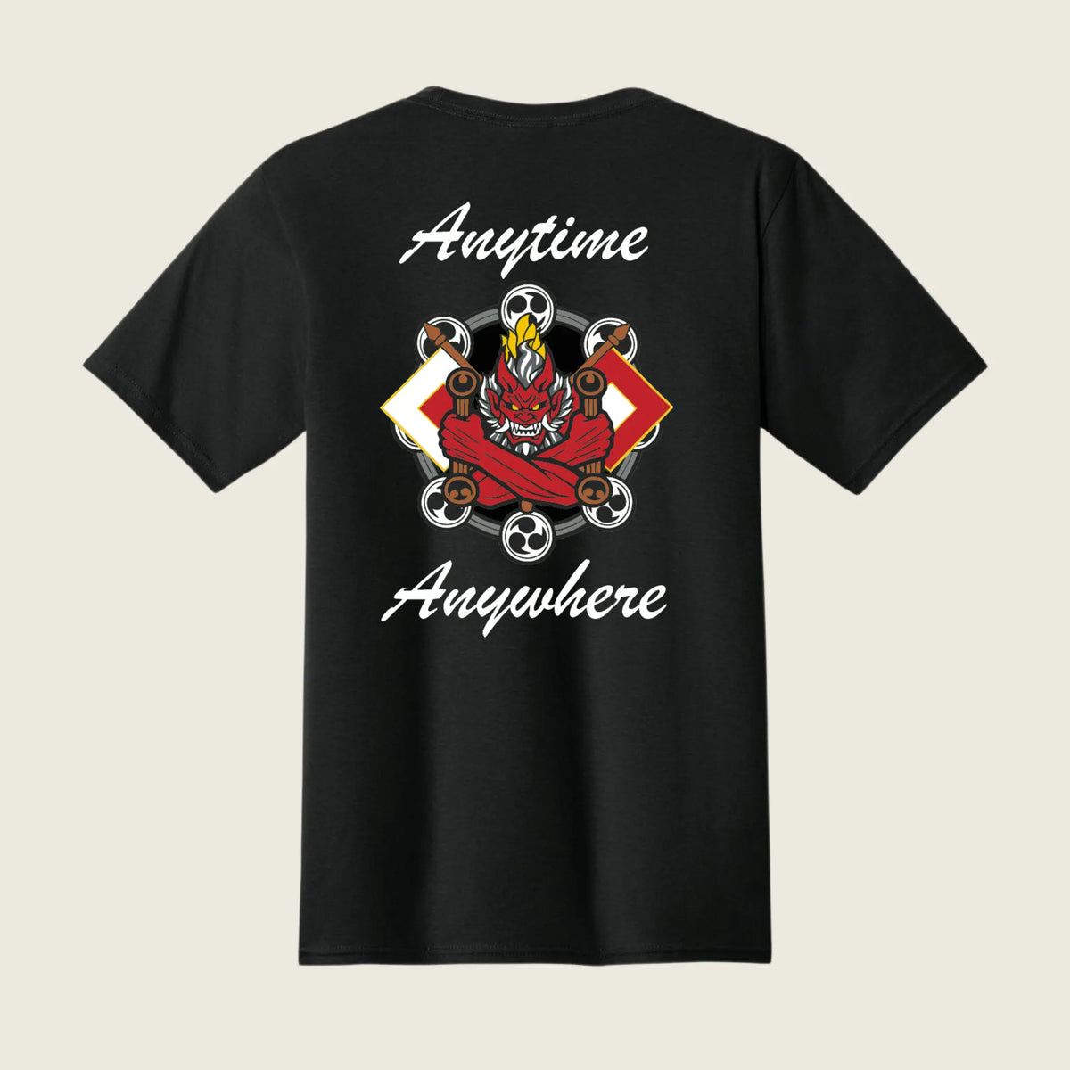 A black short-sleeve t-shirt shown from the back, featuring a graphic of a red demon riding a skateboard with flames, surrounded by white text that reads 'Anytime Anywhere' on a light beige background.