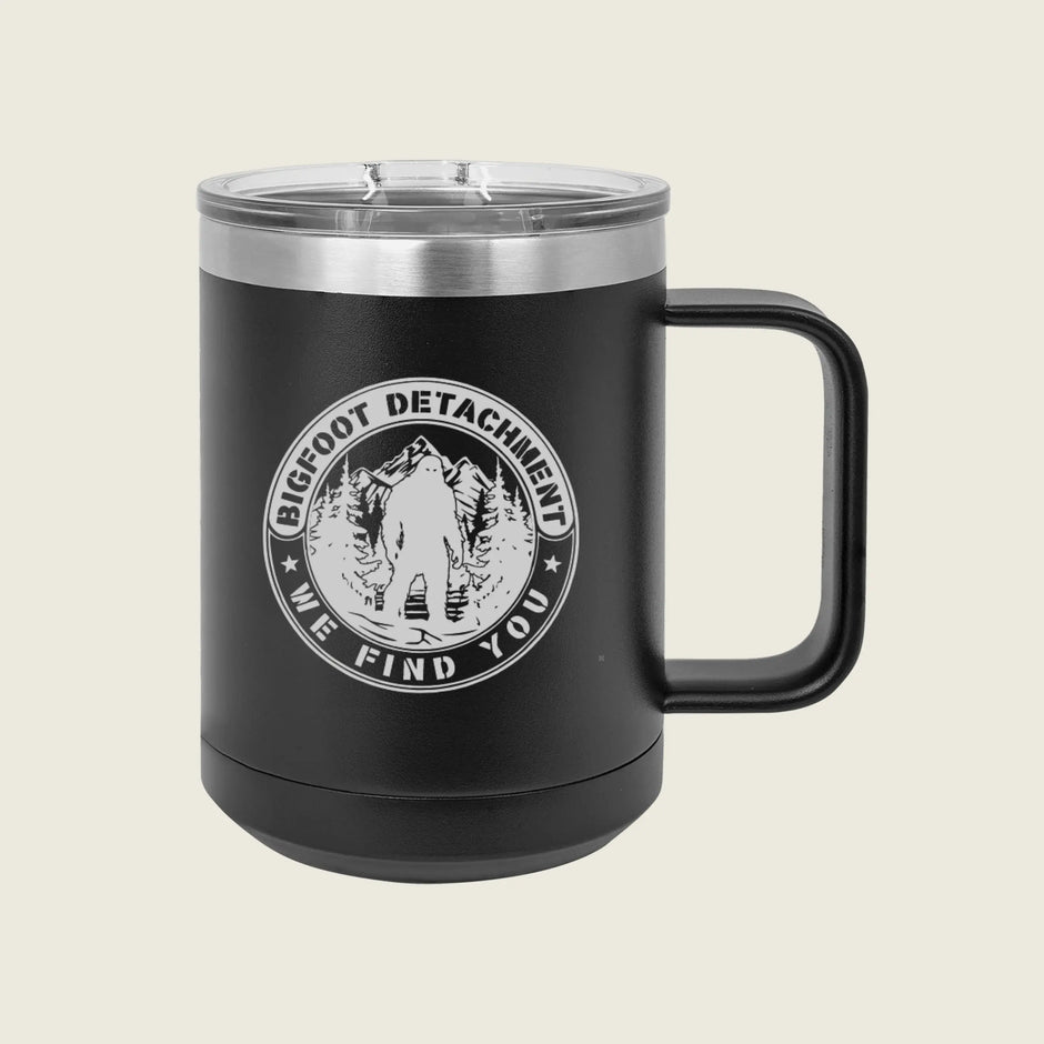 Black mug with 'Bigfoot Detachment' logo on a beige background