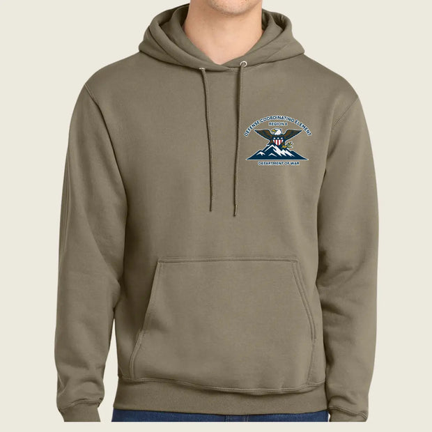 A person wearing a muted olive-brown pullover hoodie with a drawstring hood and kangaroo pocket, featuring a small embroidered United States Army Special Forces crest on the left chest, against a plain light beige background.
