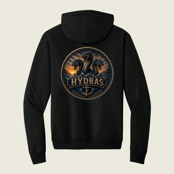 A black pullover hoodie shown from the back, featuring a large circular graphic print of three dragons with the word 'HYDRAS' and an anchor in the center, set against a light beige background