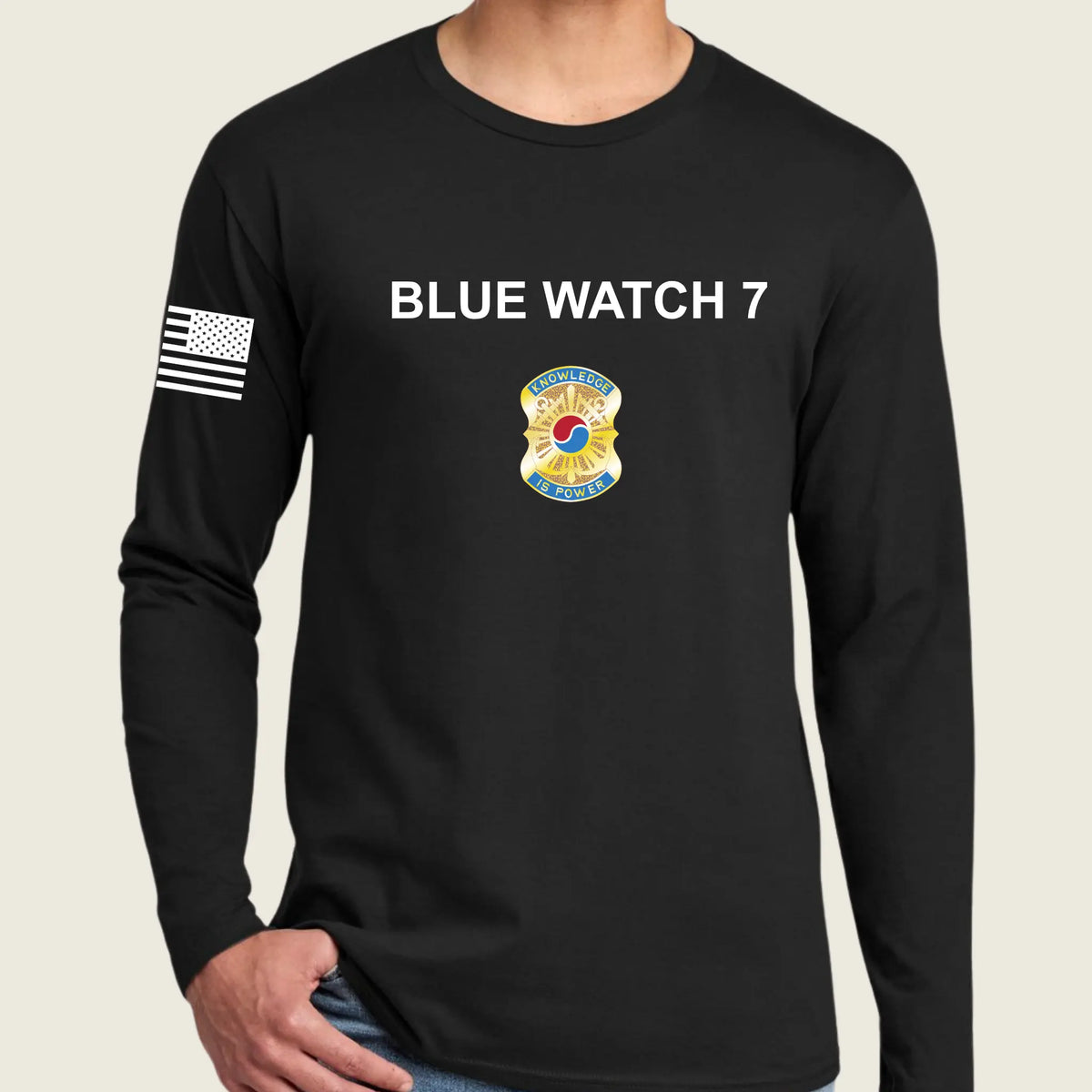 A man wearing a black long-sleeve t-shirt with 'CALL SIGN' printed in white on the chest, a army badge graphic below it, and a black-and-white American flag on the right sleeve, against a light beige background.