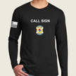 A man wearing a black long-sleeve t-shirt with 'CALL SIGN' printed in white on the chest, a army badge graphic below it, and a black-and-white American flag on the right sleeve, against a light beige background.