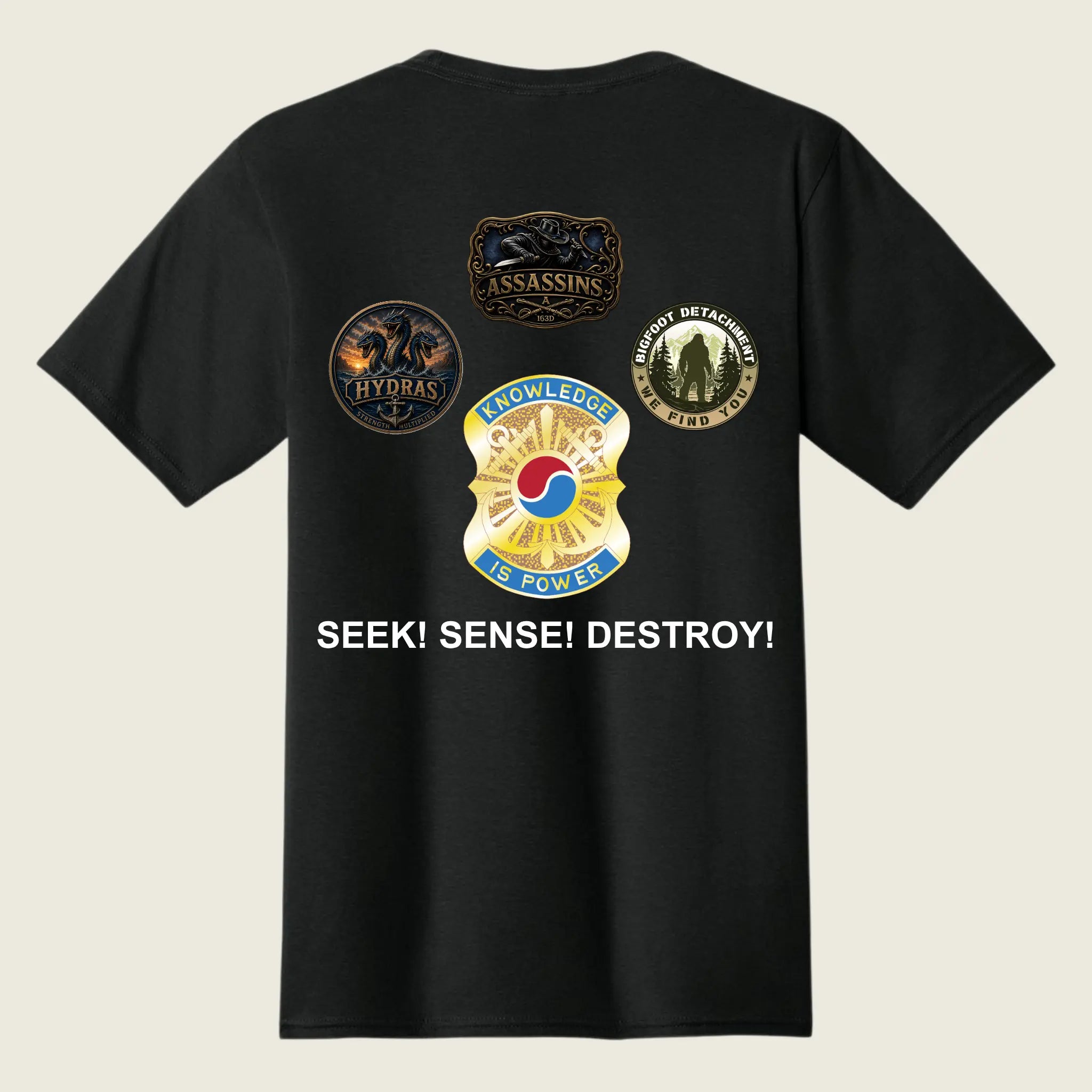 A black short-sleeve t-shirt shown from the back, featuring four military-style insignia patches and the text 'SEEK! SENSE! DESTROY!' printed in white on a light beige background.