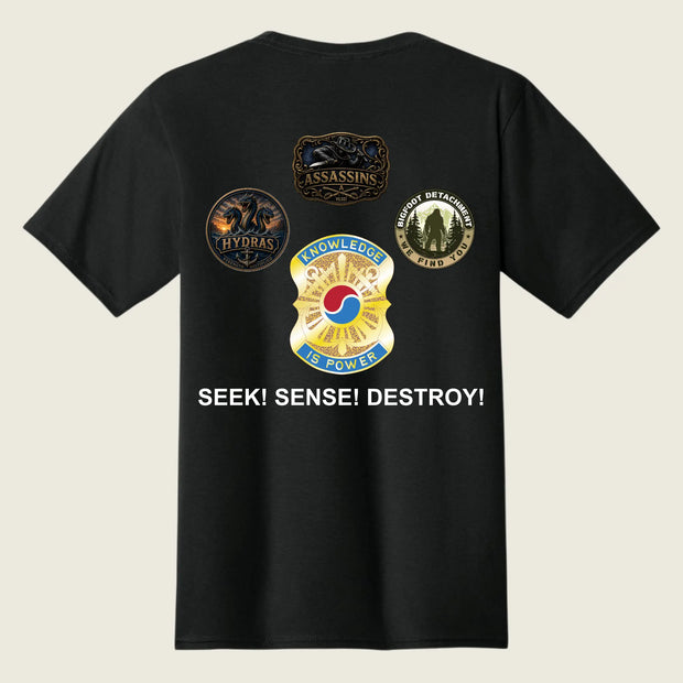 A black short-sleeve t-shirt shown from the back, featuring four military-style insignia patches and the text 'SEEK! SENSE! DESTROY!' printed in white on a light beige background.