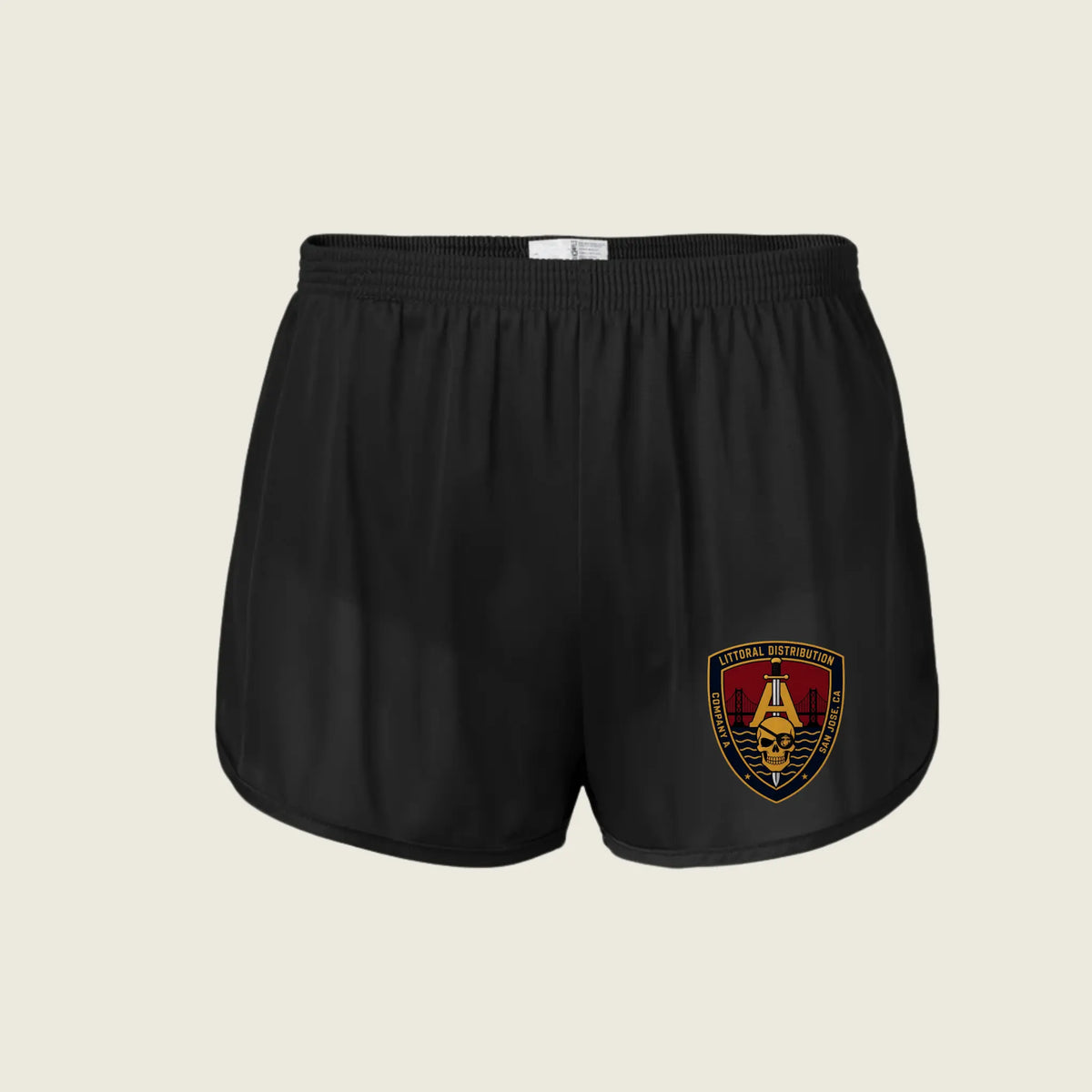 Black athletic shorts with an elastic waistband and a gold, red, and black crest patch on the left leg, displayed against a light beige background.