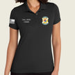 A woman wearing a black short-sleeve polo shirt with customizable white text on the left chest reading 'CALL SIGN / NAME' and a yellow, blue, and red army badge graphic on the right chest, plus a white American flag print on the sleeve.